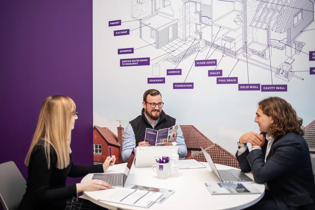 Wallpaper design showing a wire frame of a typical house in a meeting room with 3 proprety surveyors